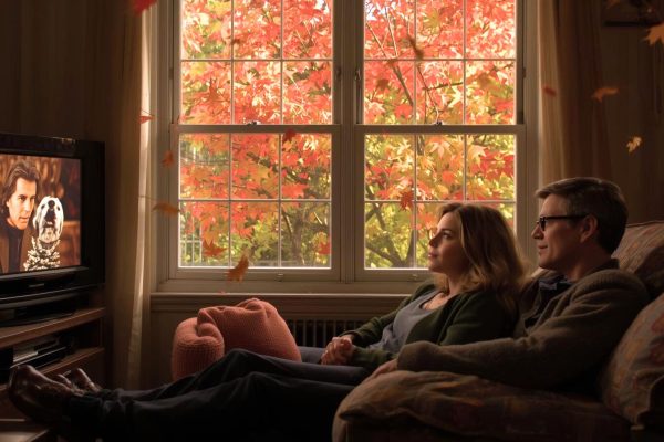мужчина и женщина сидят у телевизора, а за окном багровые листя кленовые