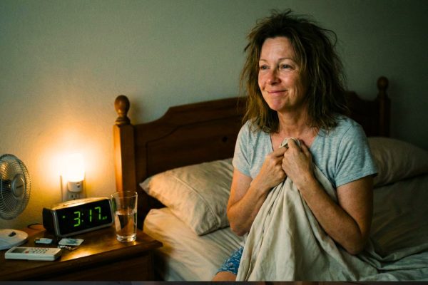 Ночные приливы при менопаузе: женщина проснулась ночью от жара и потливости, рядом вода и вентилятор